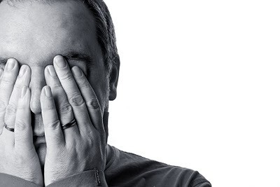 Man positioned to the far left of the frame is covering his face with his hands in this black and white image.