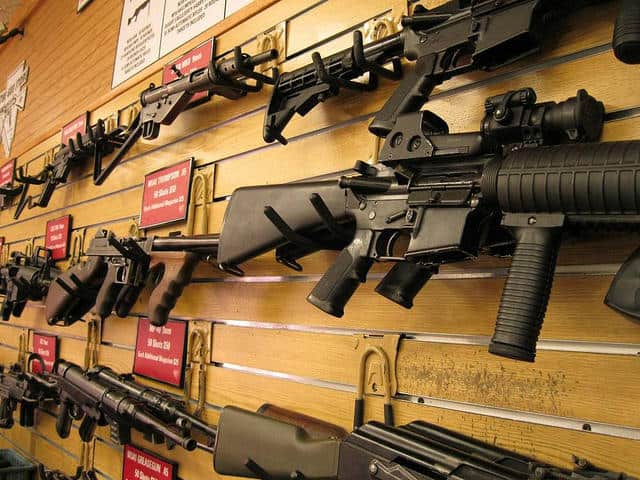 a collection of rifle type guns hanging on a wall in display